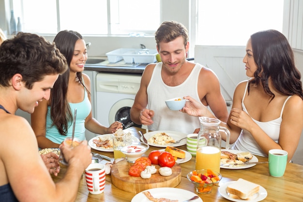 Jeune couple prenant son petit déjeuner avec des amis à la maison