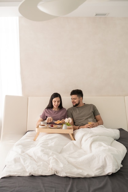 Jeune couple prenant son petit déjeuner au lit après le sommeil
