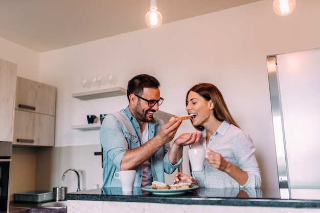Jeune couple prenant son petit déjeuner debout dans la cuisine.
