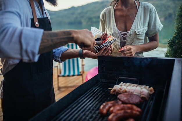 Jeune couple préparant un repas sur la jetée en bois près du lac