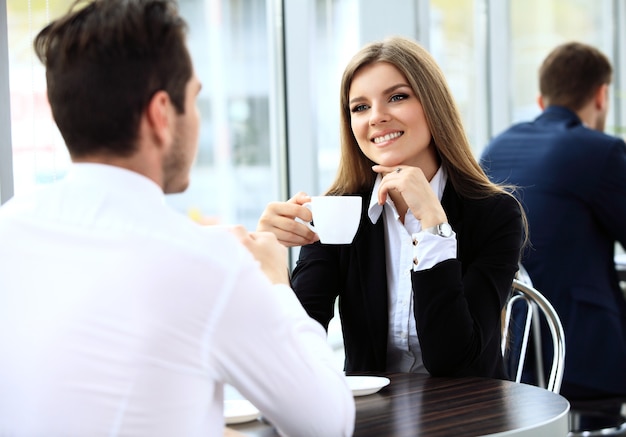 Jeune couple de professionnels discutant pendant une pause-café