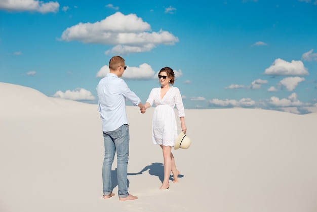 Photo jeune couple profitant du coucher de soleil dans les dunes. voyageur romantique se promène dans le désert. concept de mode de vie de voyage d'aventure