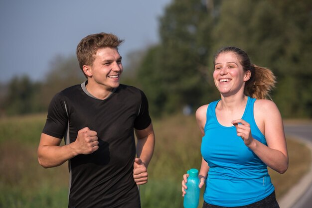 Photo jeune couple profitant d'un mode de vie sain tout en faisant du jogging le long d'une route de campagne, d'un concept d'exercice et de remise en forme