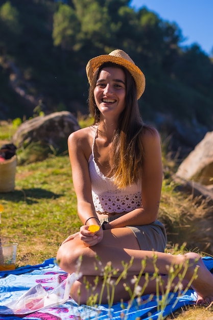 Un jeune couple de race blanche au pique-nique manger des chips dans les montagnes au bord de la mer en profitant de la chaleur