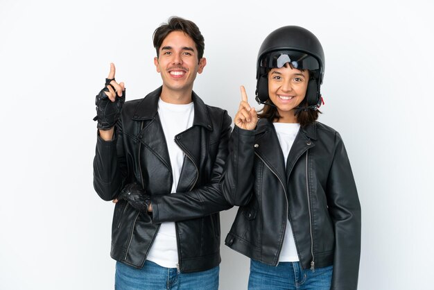 Jeune couple de race mixte avec un casque de moto isolé sur fond blanc montrant et levant un doigt en signe du meilleur