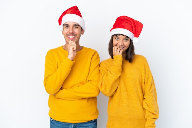 Jeune Couple De Race Mixte Célébrant Noël Isolé Sur Fond Blanc Souriant Avec Une Douce Expression