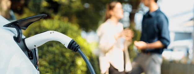 Photo un jeune couple recharge la batterie de sa voiture électrique à partir d'une station de charge.