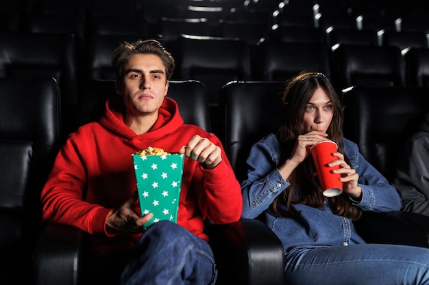 Un jeune couple regarde attentivement un film dans la salle de cinéma Popcorn et soda divertissement et loisirs