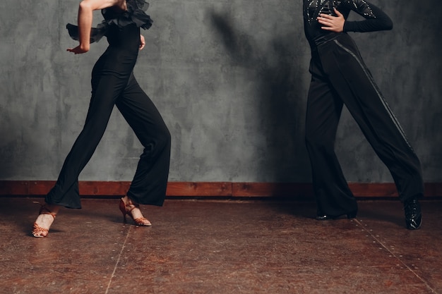 Photo jeune couple en robe noire dansant dans le chachacha de danse de salon