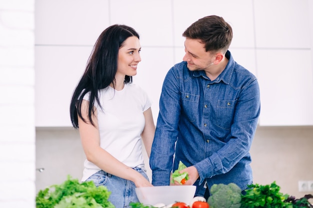 Un jeune couple romantique cuisine ensemble dans la cuisine en passant un bon moment ensemble.