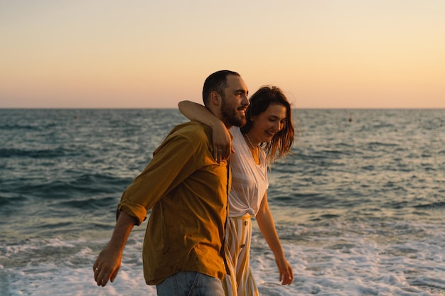 Jeune couple romantique dansant se retournant au bord de la mer Paysage marin au coucher du soleil avec un beau ciel Couple romantique sur la plage au coucher du soleil doré Couple amoureux s'amusant sur la plage