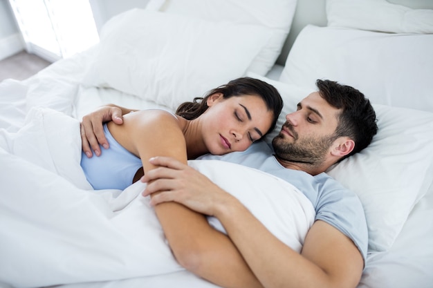 Jeune couple romantique dormant sur le lit dans la chambre