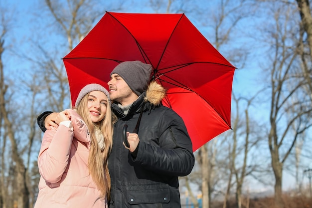 Jeune couple romantique avec parapluie lumineux le jour d'hiver ensoleillé