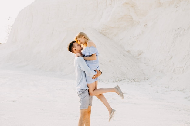 Jeune couple romantique en s'amusant, à l'extérieur. Homme tenant la femme dans ses bras, souriant.