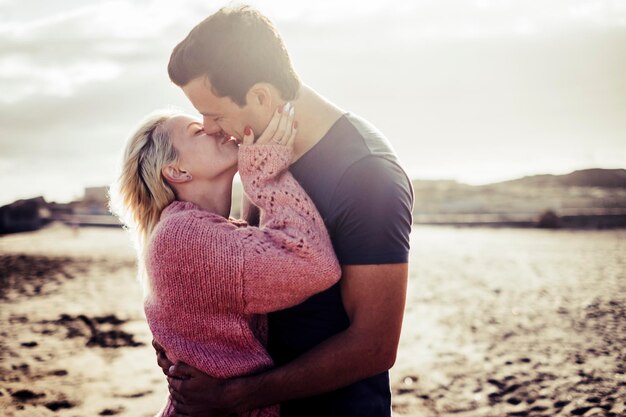 Photo un jeune couple romantique s'embrasse sur la plage.