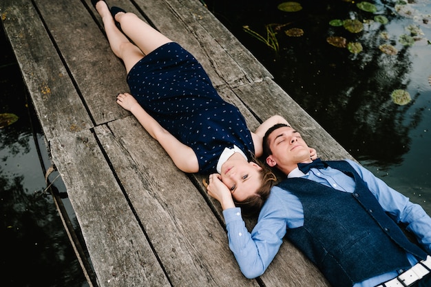 Jeune couple s'allonger sur un pont en bois sur l'eau de fond