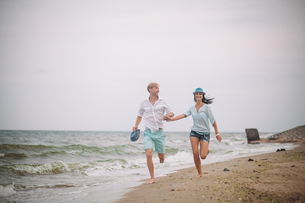 Jeune couple s'amuse le jour d'été à la plage