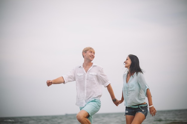 Jeune couple s'amuse le jour d'été à la plage