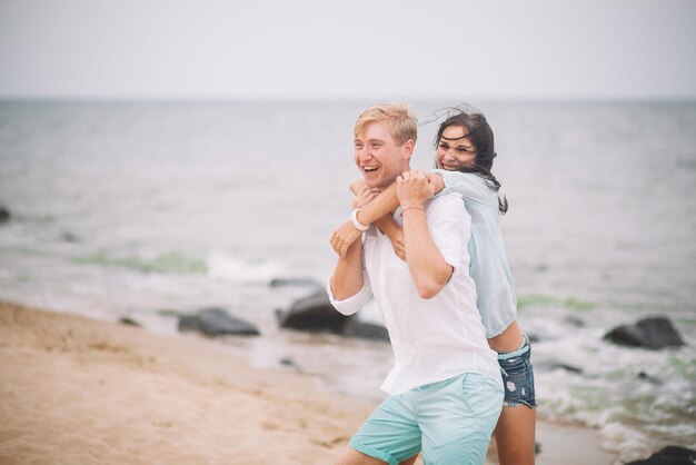 Jeune couple s'amuse le jour d'été à la plage