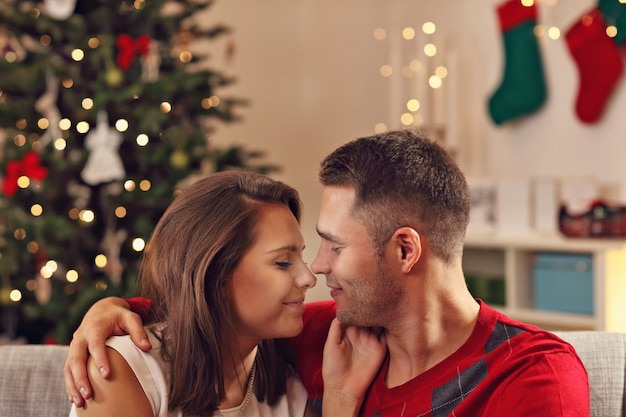 Jeune couple s'embrassant sur l'arbre de Noël