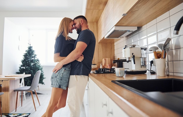 Jeune couple s'embrassant dans la cuisine le matin.