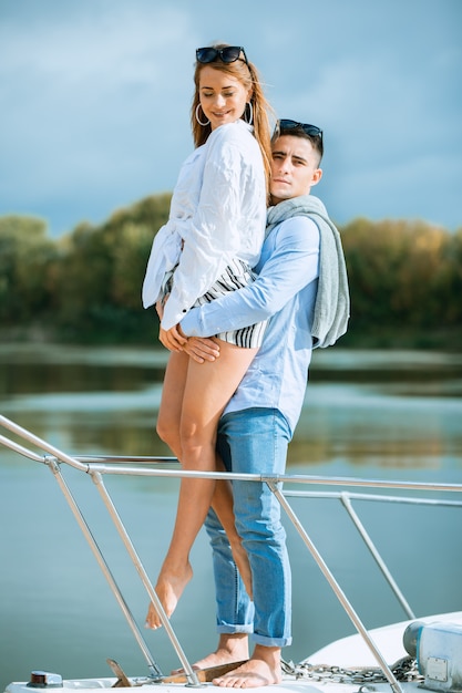 Jeune couple s'embrassant sur le pont du voilier. Couple romantique sur un bateau de plaisance. Heureux homme riche et une femme en bateau privé ont un voyage en mer. Couple en lune de miel voyageant avec yacht