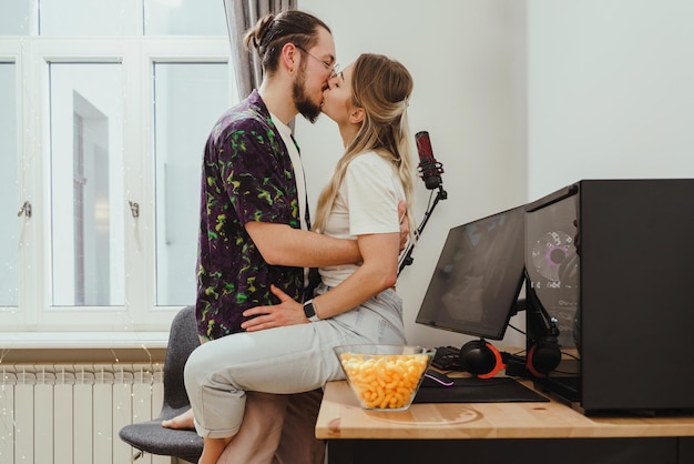 Jeune couple s'embrassant sur la table avec un ordinateur personnel de jeu