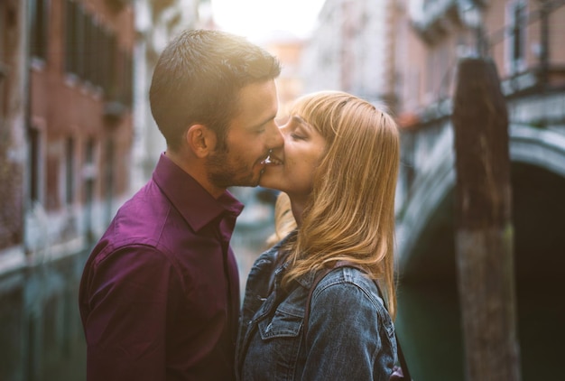 Un jeune couple s'embrasse à l'extérieur.
