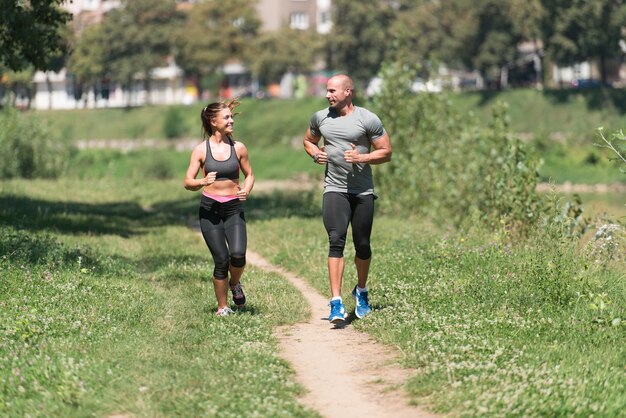 Jeune couple s'exécutant dans la forêt boisée de formation et d'exercice pour Trail Run Marathon Endurance Fitness Mode de vie sain Concept