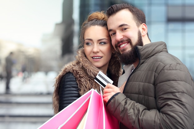 Photo jeune couple avec des sacs à provisions et carte de crédit dans la ville