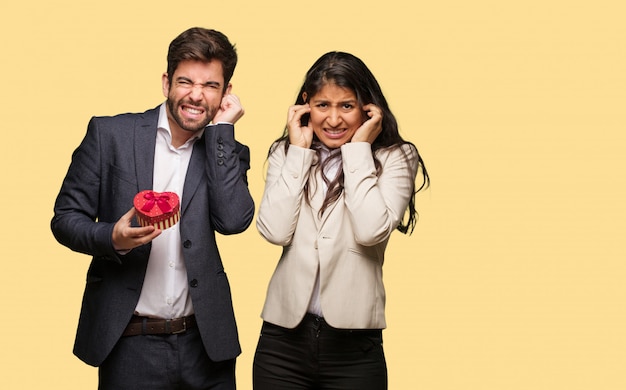 Jeune couple, saint valentin, couvrir, oreilles, à, mains