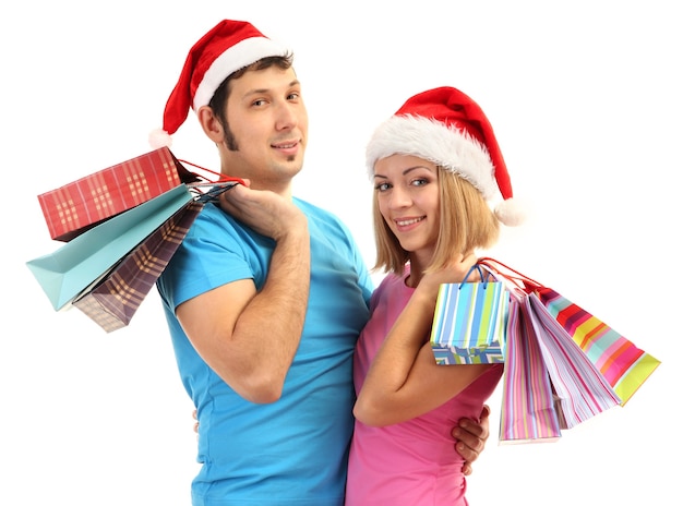 Jeune couple à Santa hats shopping et tenant de nombreux sacs à provisions isolés