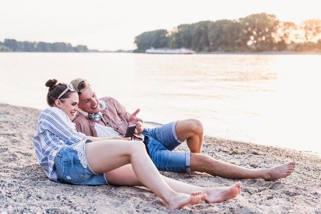 Photo jeune couple se détendre au bord de la rivière