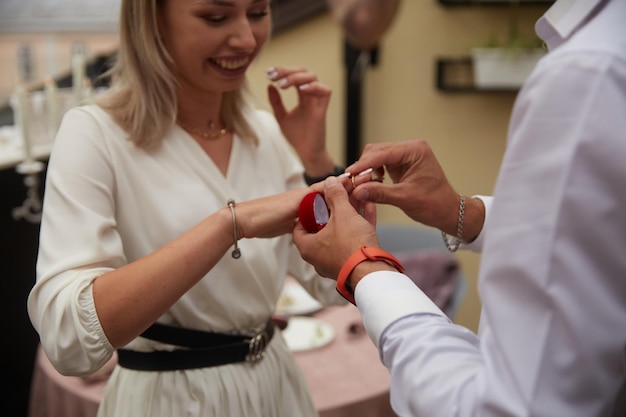 Photo un jeune couple se fiance un homme propose une nouvelle bague de fiançailles à une fête de famille