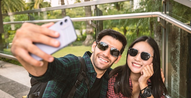 Un jeune couple se prend un selfie debout à l'extérieur