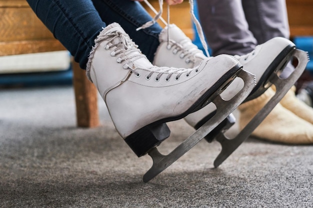 Jeune couple se préparant à un patinage. Photo en gros plan de leurs mains attachant des lacets de patins de hockey sur glace