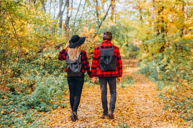 Jeune couple se promène dans la forêt d'automne main dans la main