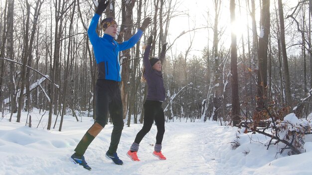 Jeune couple se réchauffant dans la forêt d'hiver