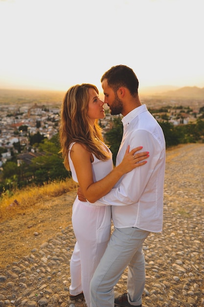 Un jeune couple se regarde face à face alors qu'ils se tiennent dans la ville au coucher du soleil.