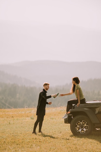 Jeune couple se reposant sur un capot de véhicule tout-terrain à la campagne