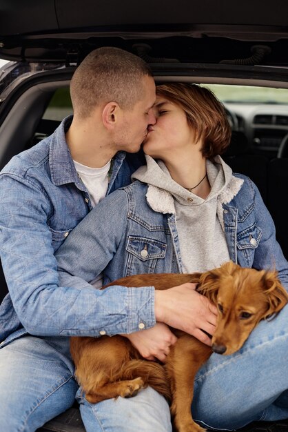 Jeune couple se reposant dans la voiture avec leur chien.