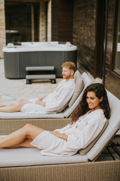 Jeune couple se reposant sur des lits sur la terrasse extérieure