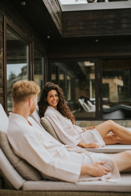 Jeune couple se reposant sur des lits sur la terrasse extérieure