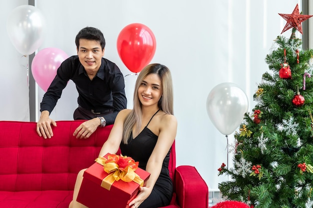 Photo un jeune couple séduisant célèbre noël et le nouvel an ensemble homme donnant une boîte cadeau à une femme