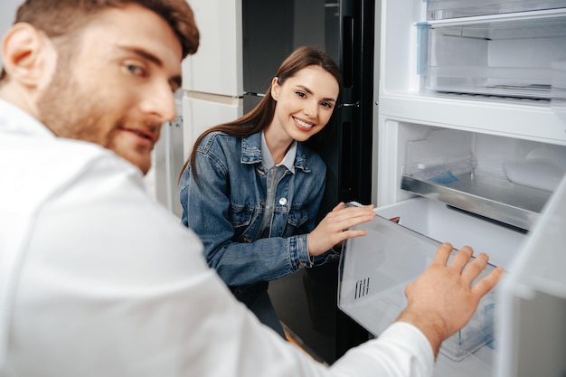 Jeune couple sélectionnant un nouveau réfrigérateur dans un magasin d'électroménagers