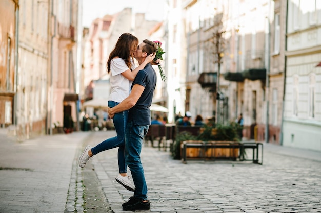 Jeune couple souriant avec un bouquet de fleurs amoureux s'embrassent dans l'amour à l'extérieur Amour et tendresse romance datant concept de style de vie