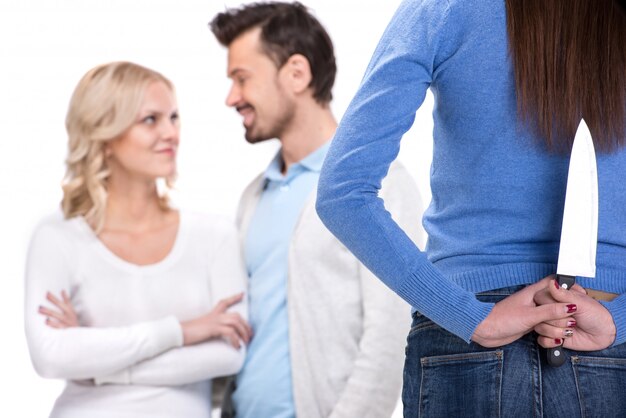 Jeune couple souriant et une femme avec un couteau qui les regarde.