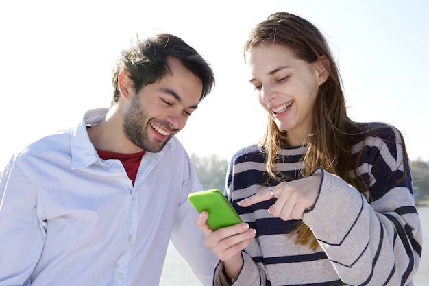 Jeune couple souriant et regardant le téléphone mobile