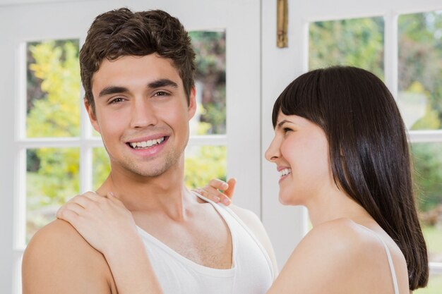 Jeune couple souriant et se faisant des câlins dans le salon