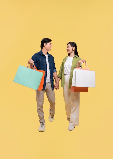 Un jeune couple souriant tenant des sacs d'achat après un voyage d'achat marchant main dans la main